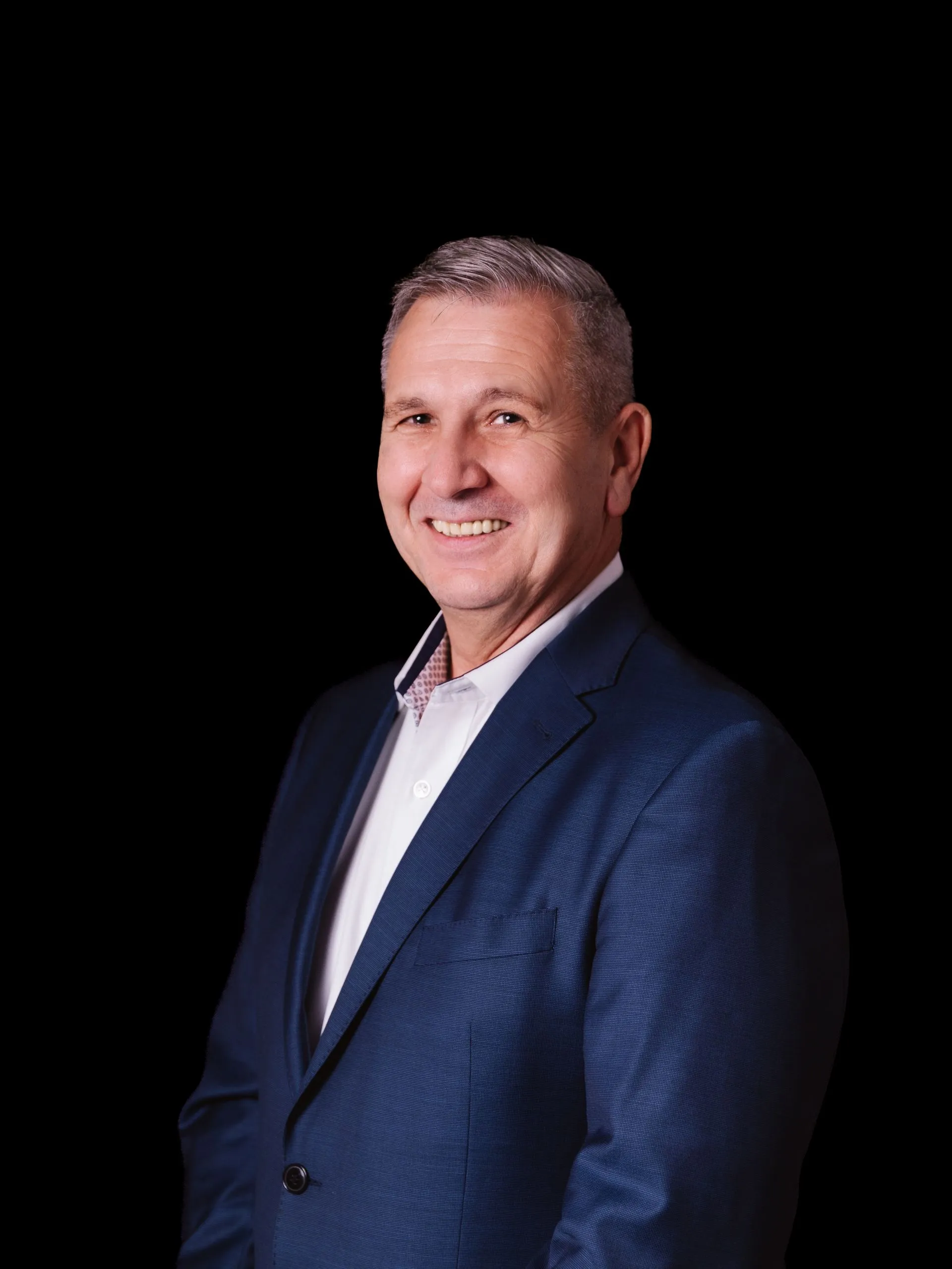 Business-Portrait eines Mannes im blauen Anzug vor schwarzem Hintergrund